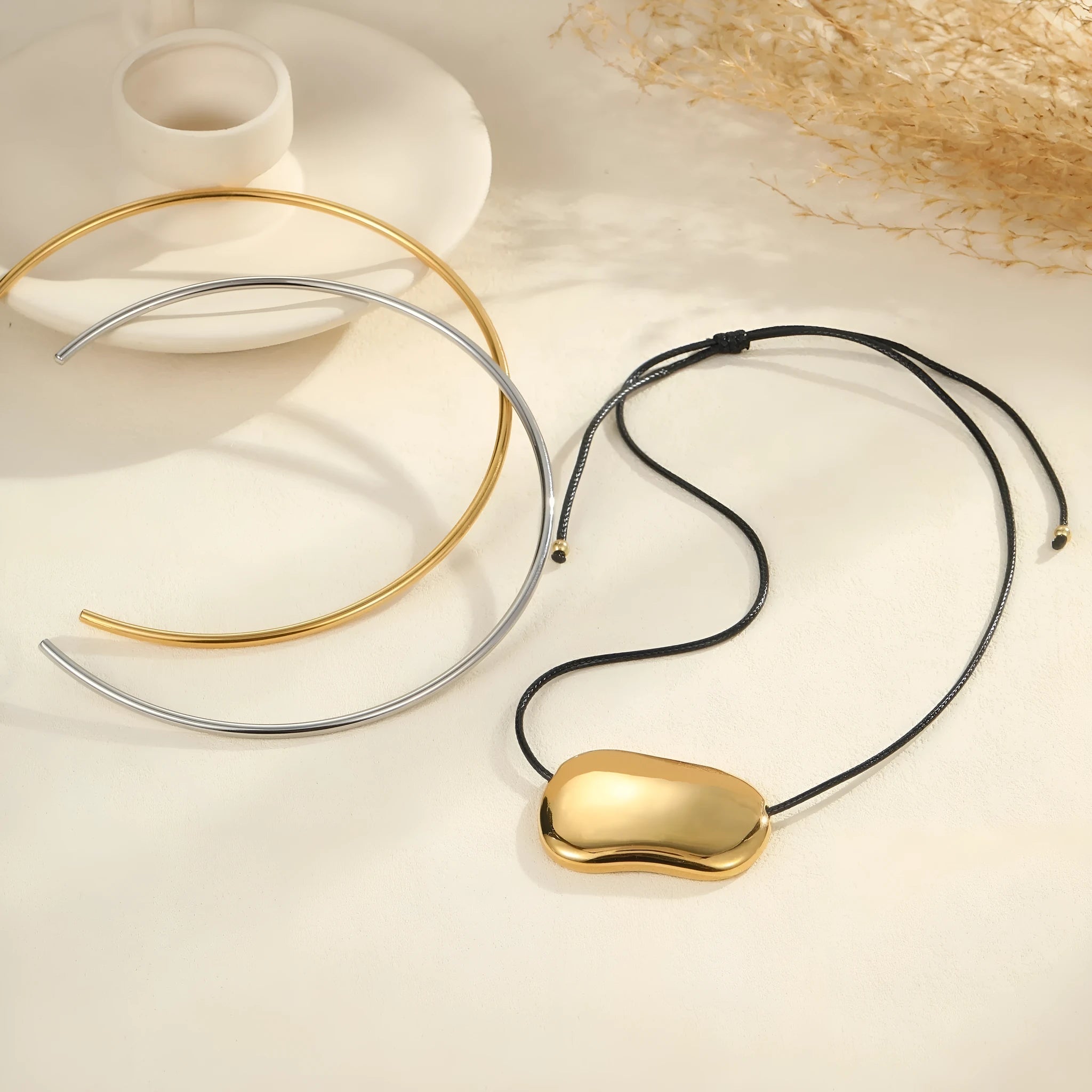 Gold or silver stainless steel necklace with black rope chain and irregular geometry pendant, shown next to a matching collar option.