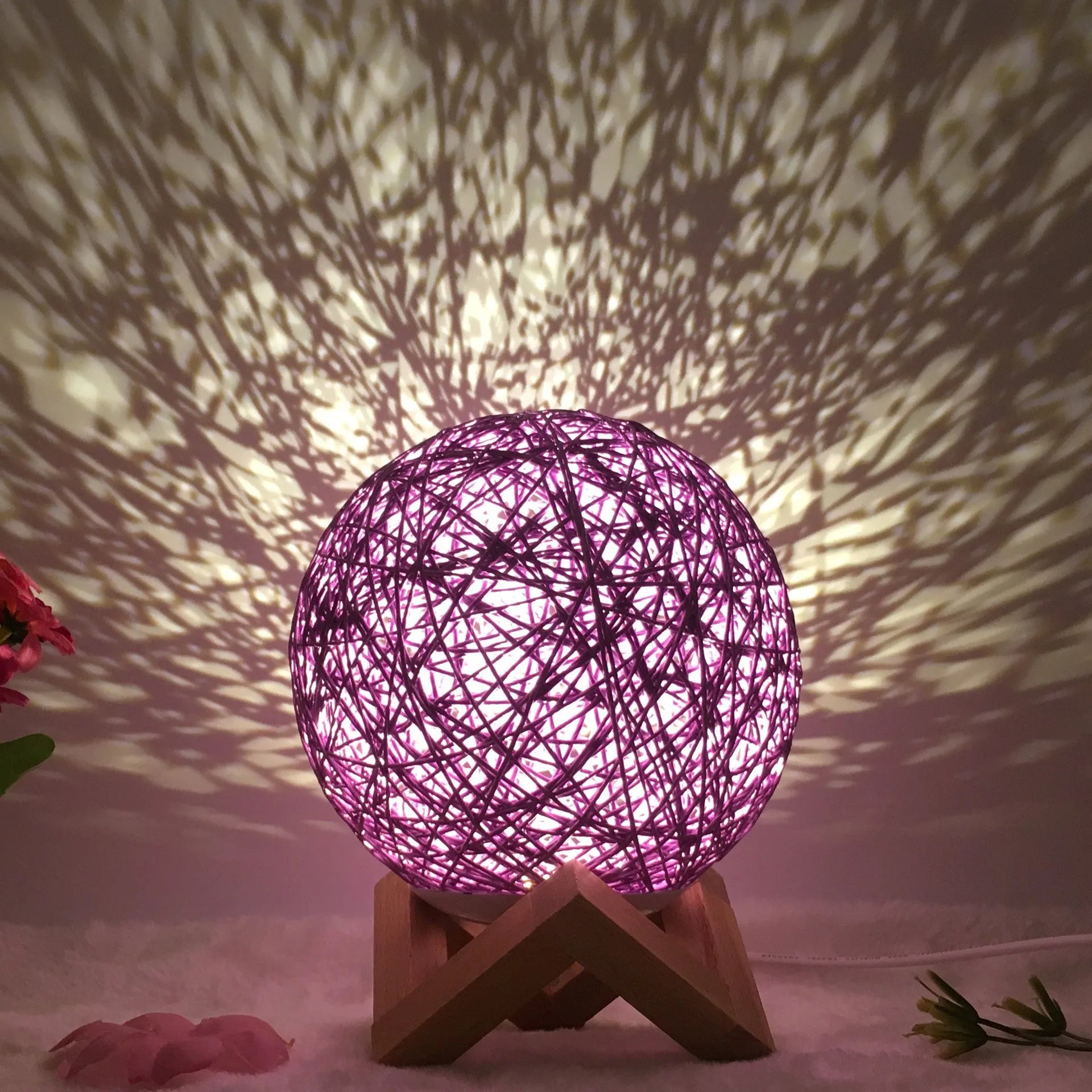 Rattan ball table lamp with woven shade and warm LED lighting on wooden surface
