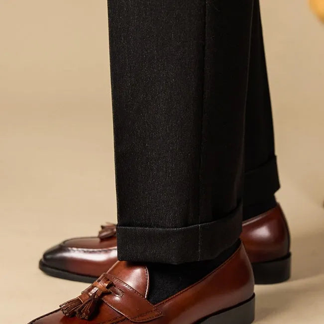 Men's black polished leather tassel loafers with rubber sole, shown from the side.