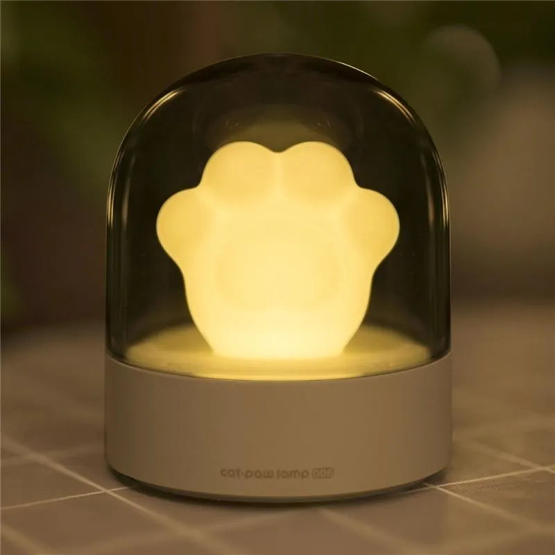 Grey cat paw shaped USB rechargeable musical night light on a wooden desk