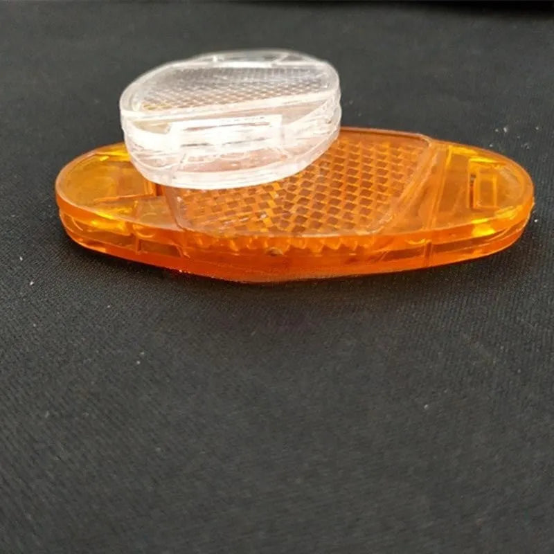 White and yellow plastic bicycle spoke reflectors showing 7.2cm length measurement
