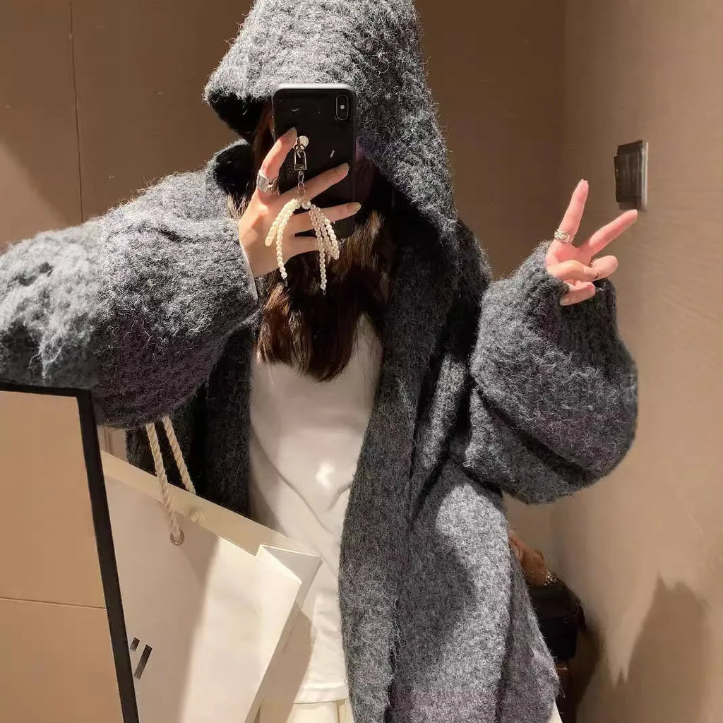 Woman wearing a thick dark grey hooded zip-up cardigan, loose fit.