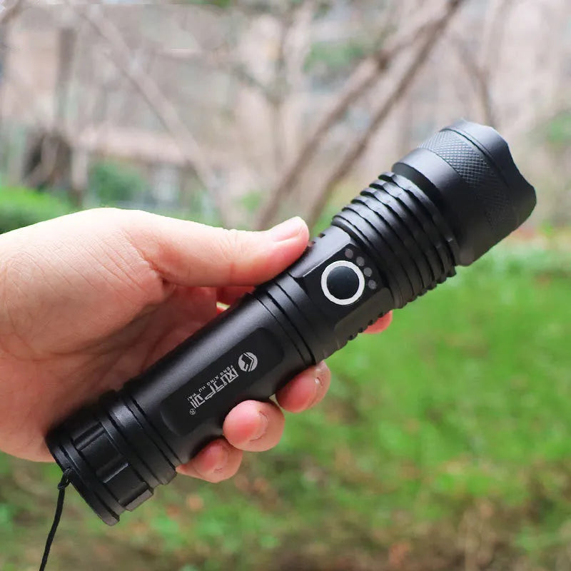 Black aluminium alloy LED flashlight with zoom lens on plain background
