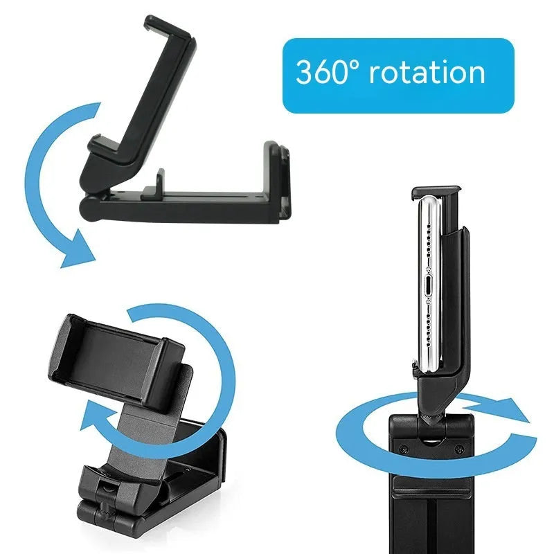 Black foldable ABS phone holder with 360-degree rotation on a desk next to a smartphone