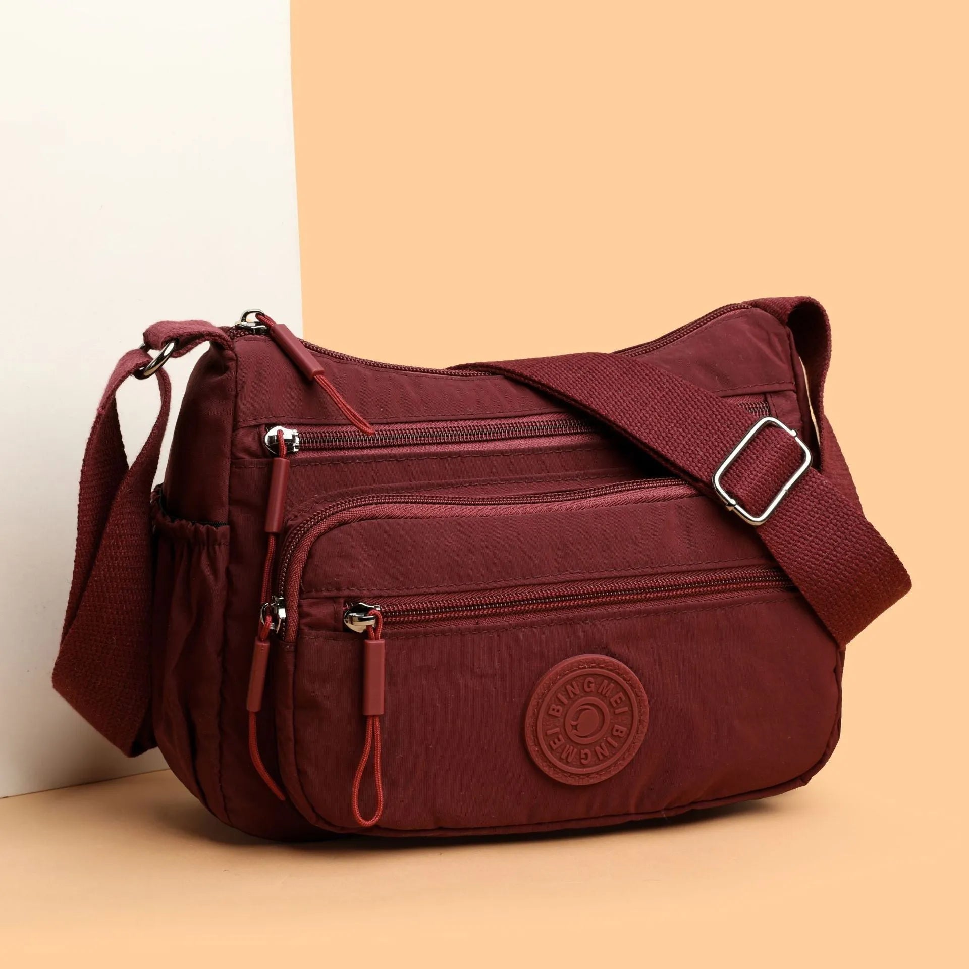 Soft nylon crossbody bag in black, grey, or red with a single shoulder strap and water-repellent finish.