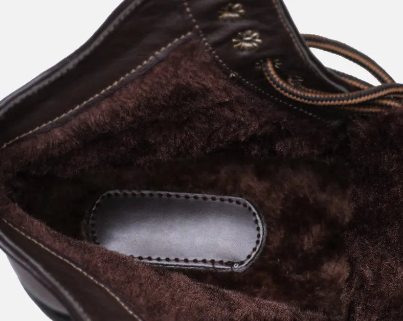 Men's brown embossed leather Martin boots with mid-top cut, round toe, thick heel, and front strap on a wooden floor