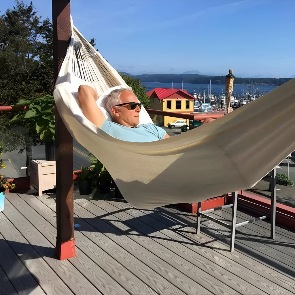 Cotton camping hammock with strap and bandage set up between trees for outdoor use