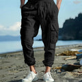 Men's loose-fit linen trousers with ankle ties, multiple pockets, and a drawstring waist in a solid colour.