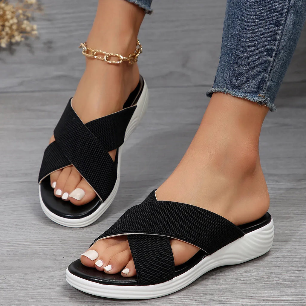 Women's black flat wedge peep-toe summer slippers with a cross-strap design on a rubber sole.