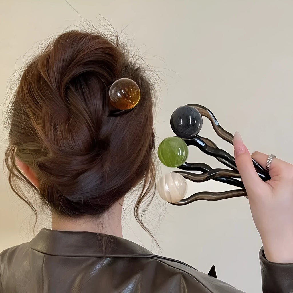 A set of U-shaped acrylic hair barrettes with a ball detail in beige, caramel, dark grey, and green colours