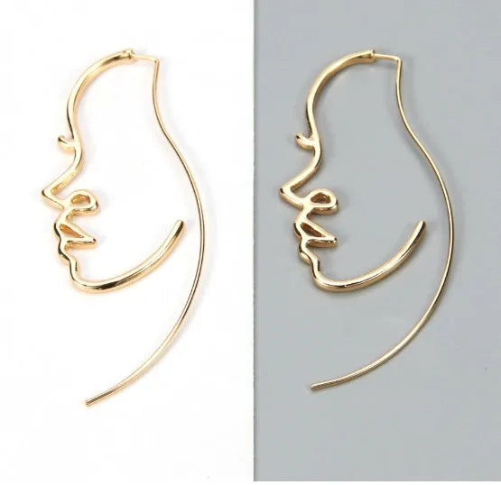 Creative abstract face contour earrings in metal gold finish on a white background