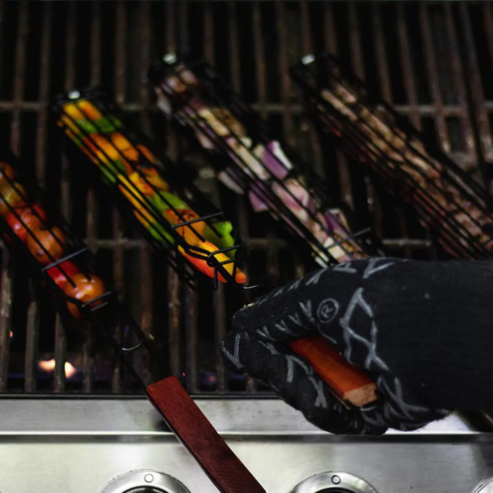 BBQ grill mesh basket with rotary lid and long wood handle placed on a metal grill outdoors