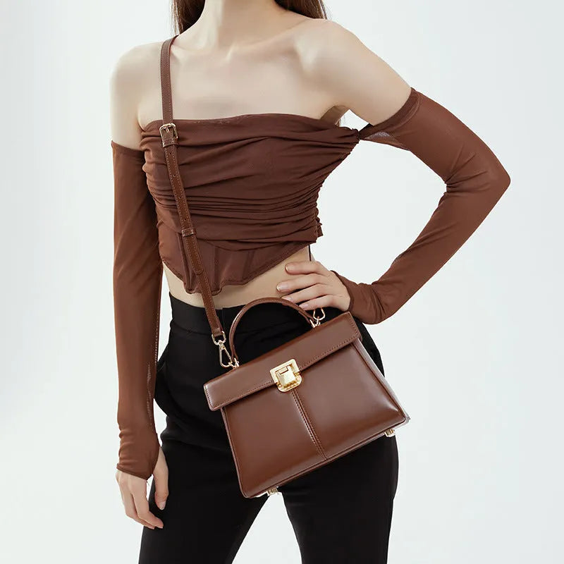 Black genuine leather women's shoulder bag with a clasp closure and long adjustable strap.