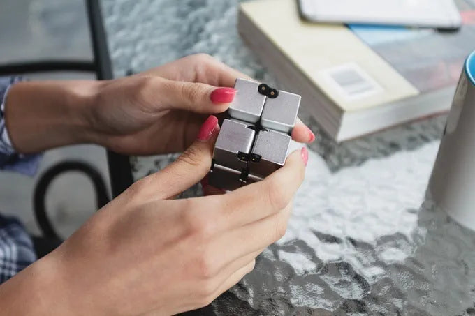 Zinc alloy infinity cube fidget toy showing black and silver rotating cube puzzle on a desk.