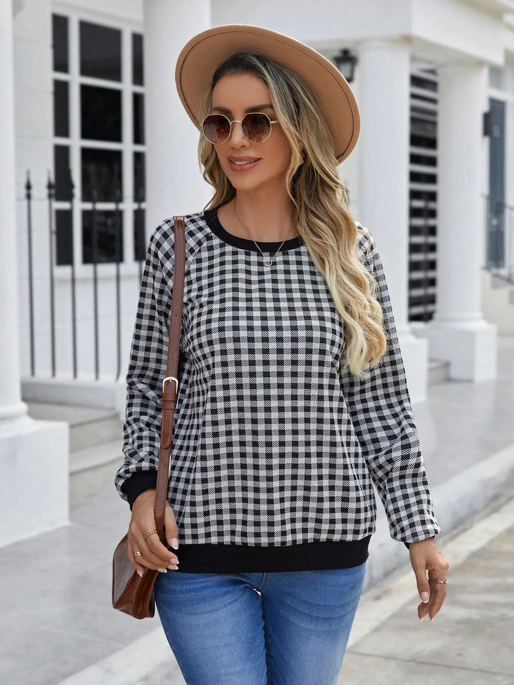 Black and white plaid print long sleeve pullover sweater for men on a neutral background.