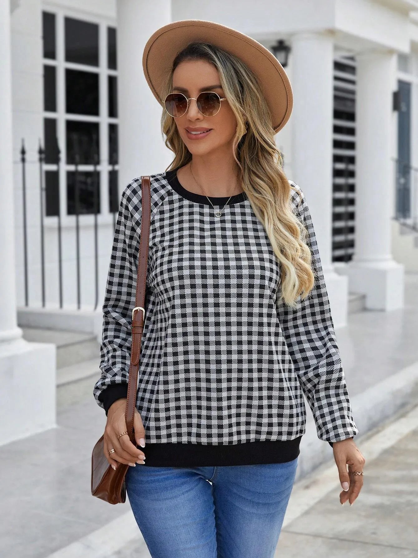 Black and white plaid print long sleeve pullover sweater for men on a neutral background.
