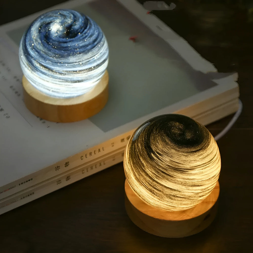 Planet-shaped USB night light on its base with soft multi-colour glow