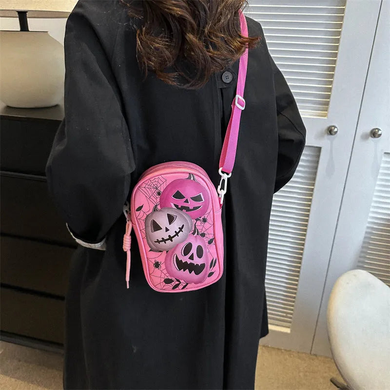 Black Halloween crossbody bag with orange pumpkin, white ghost, and bat graffiti print, shown on a model.
