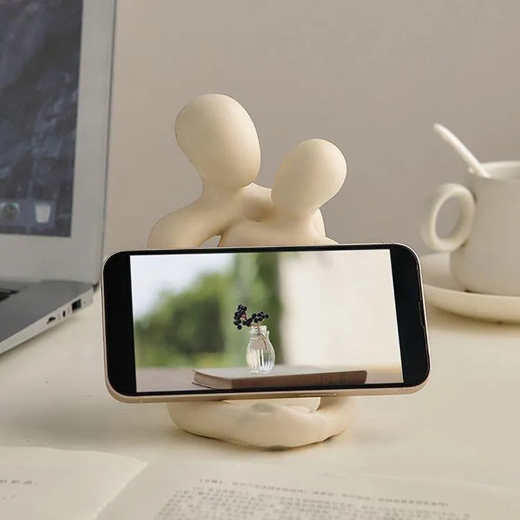 Modern loving couple resin statue in milky white or gold colour on a wooden desk.