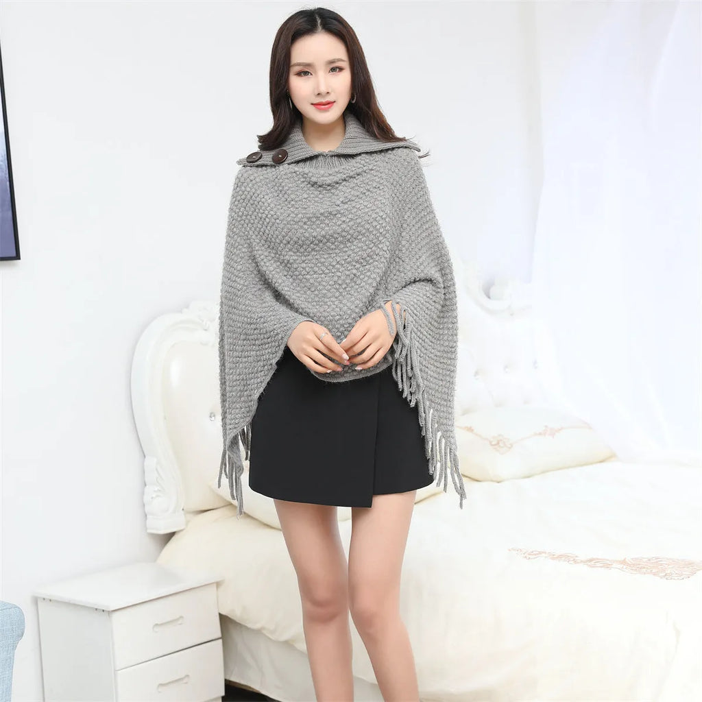Sleeveless polka dot knit cloak in apricot colour, shown as a vest on a hanger.