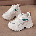Women's white and beige height increasing sports trainers with cross shoulder straps and lace-up front.