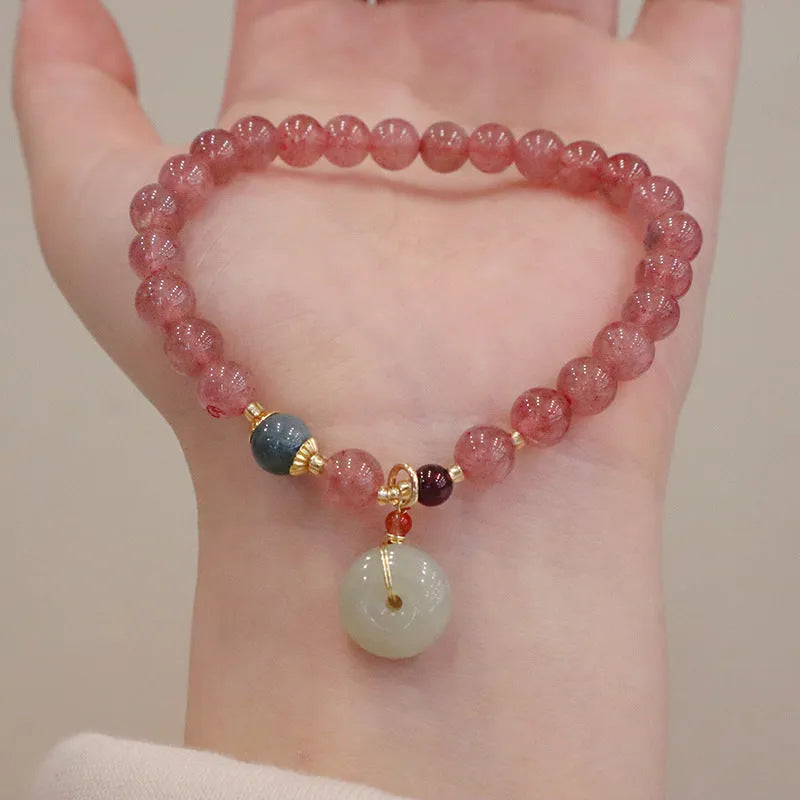 Women's strawberry quartz bracelet with geometric stones, purse charm and lucky bagg charm on wrist