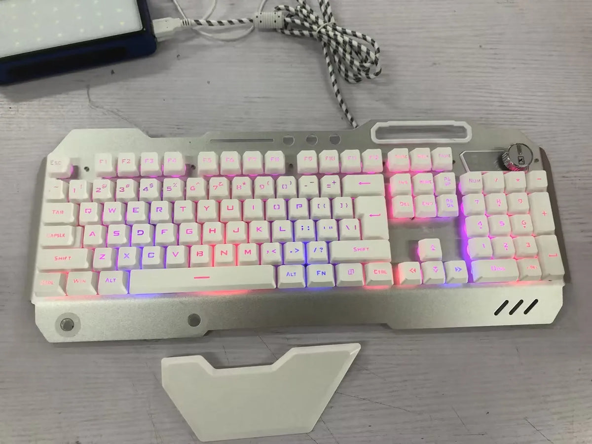 Black wired gaming keyboard with RGB backlight, phone holder, pen tray, and magnetic wrist rest on a desk