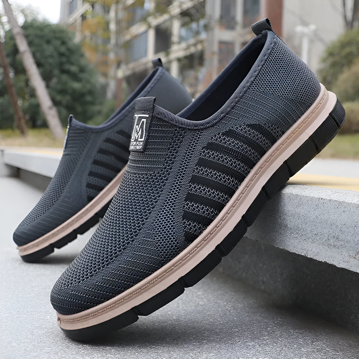 Men's slip-on casual sneakers with black mesh upper, low top, flat heel, and round toe.