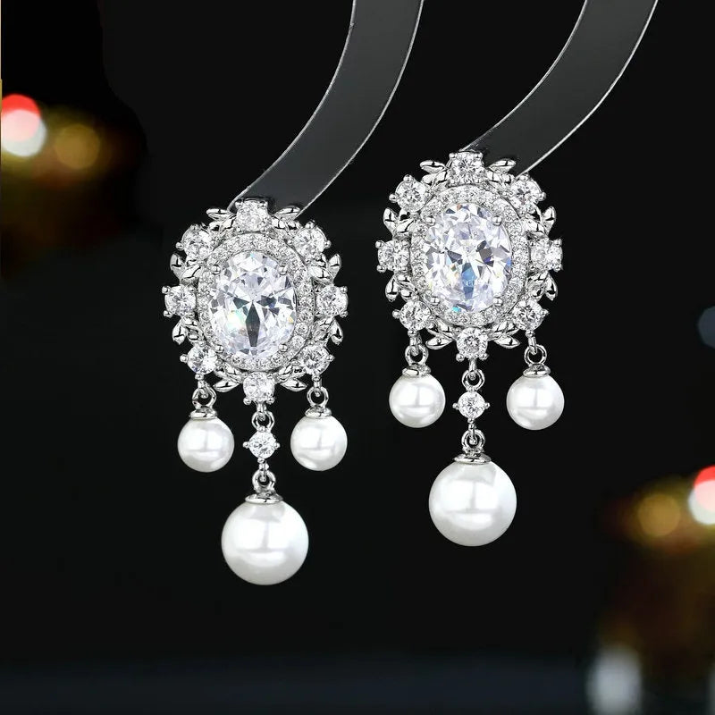 Pair of oval copper earrings with inlaid zircon and a white pearl tassel drop.