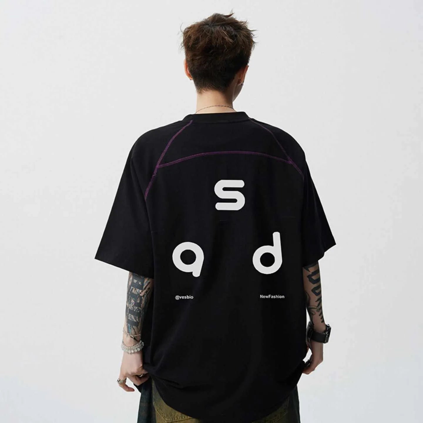 Man wearing a loose-fitting black cotton T-shirt with a white letter print on the chest.