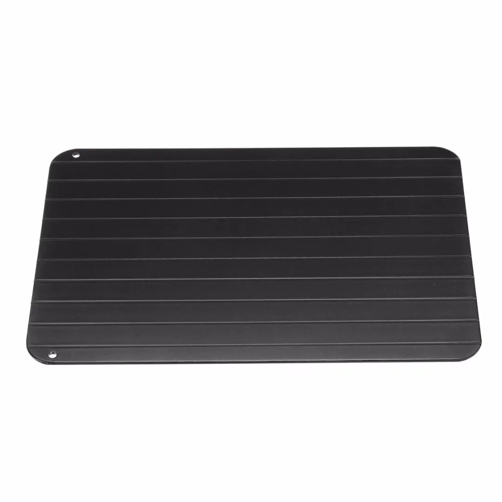 Black aluminium fast defrosting tray with silica gel feet on a kitchen countertop.