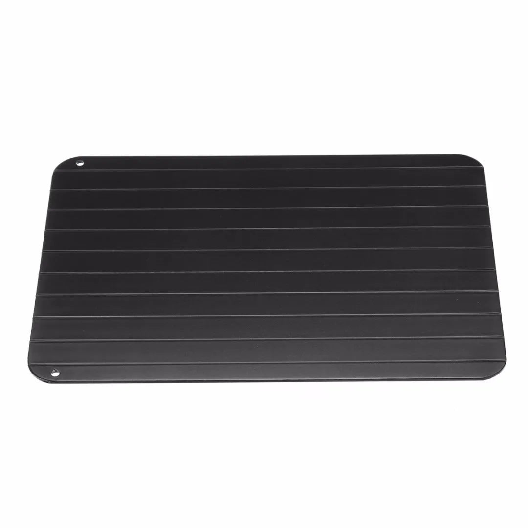 Black aluminium fast defrosting tray with silica gel feet on a kitchen countertop.