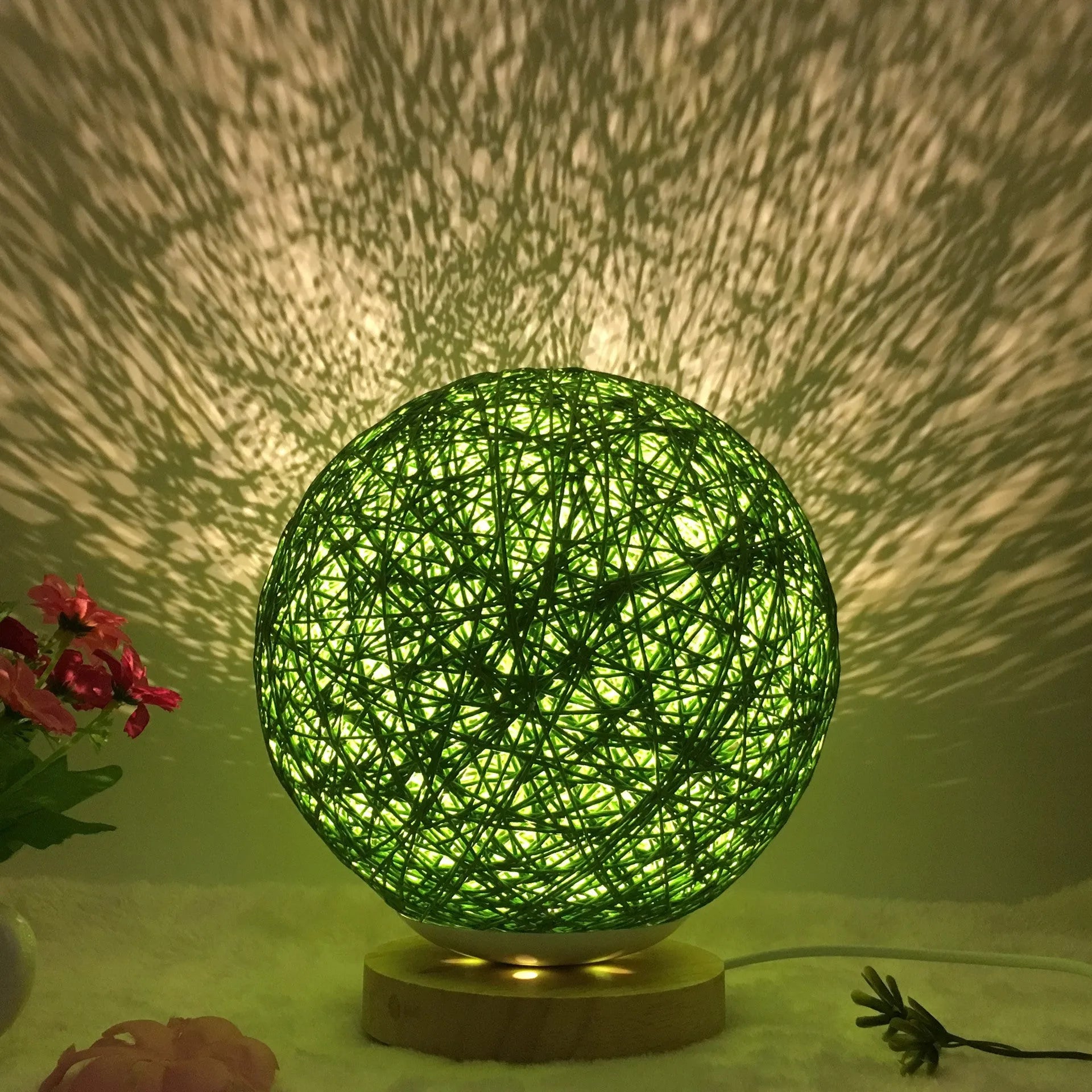 Rattan ball table lamp with woven shade and warm LED lighting on wooden surface