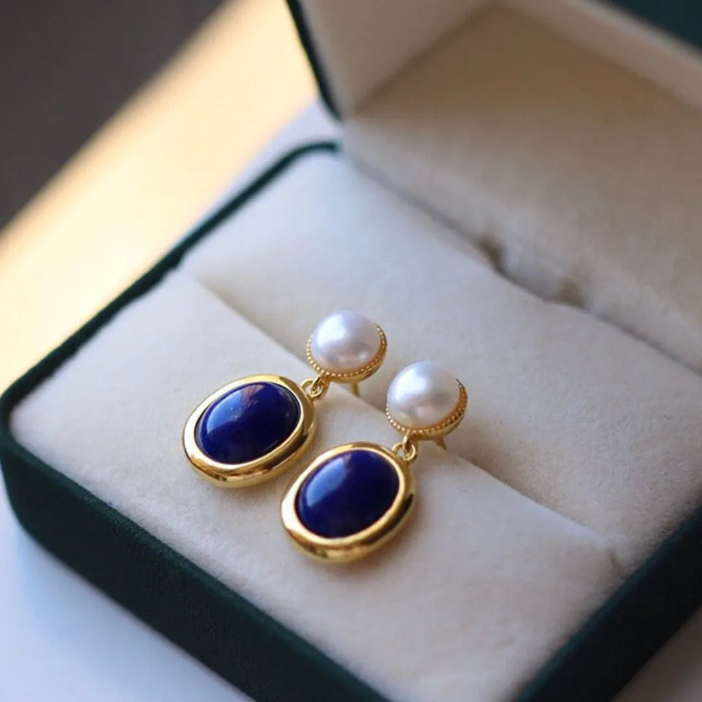 A pair of simple drop earrings featuring a blue lapis lazuli pearl set in patterned sterling silver.