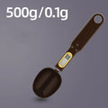 Black electronic measuring spoon scale on a kitchen counter showing digital display.