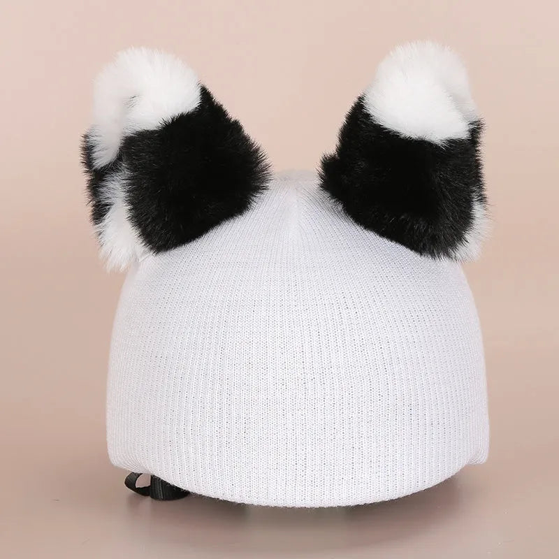 Soft plush cartoon character topper fitting over a blue ski helmet on a snowy background.