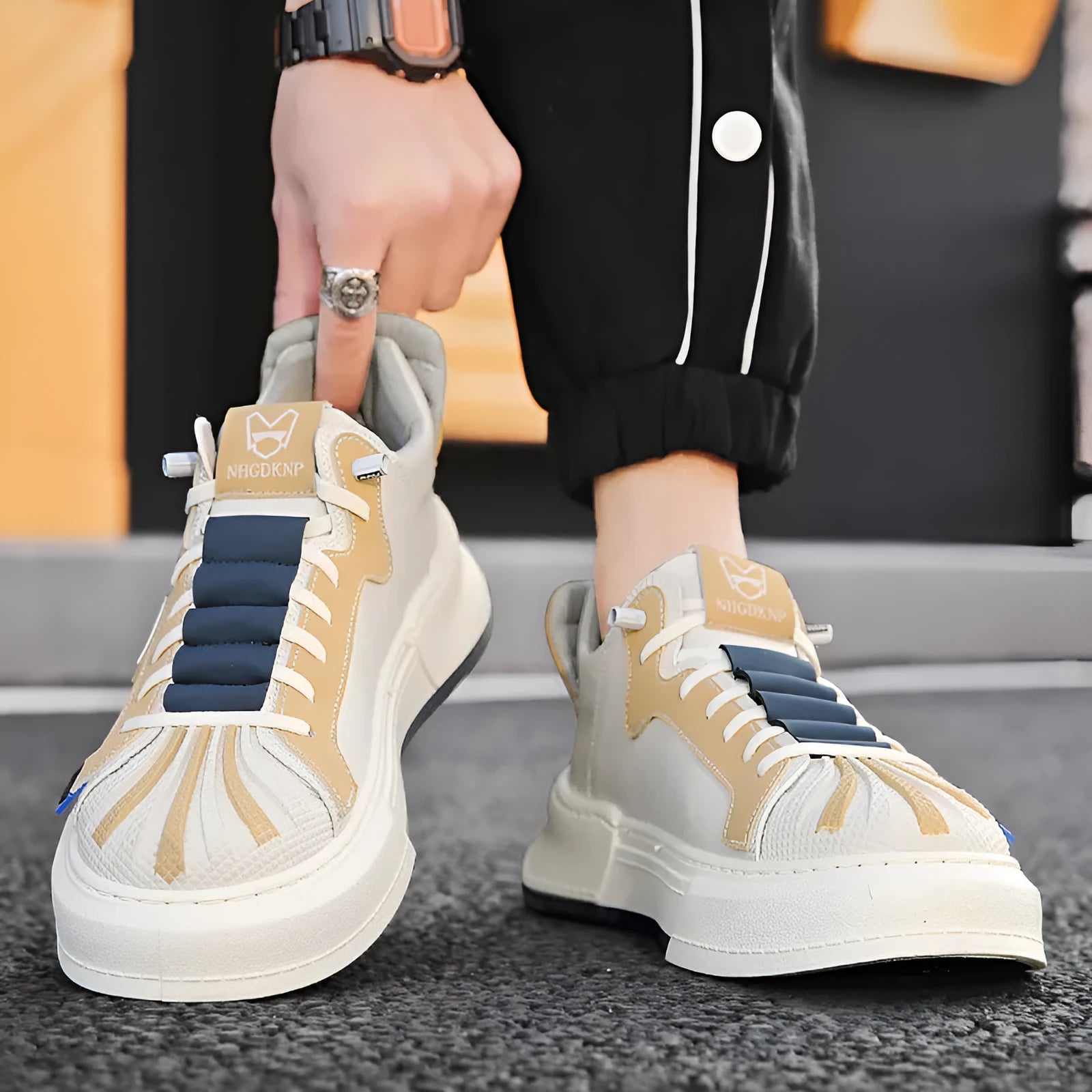 Men's beige and black low-top casual sneakers with elastic band fastening and mesh lining.