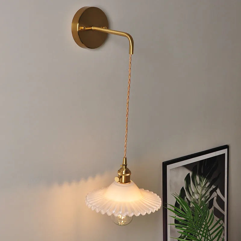 Retro brass lotus wall lamp with glass shade mounted on a wall, showing copper fittings.