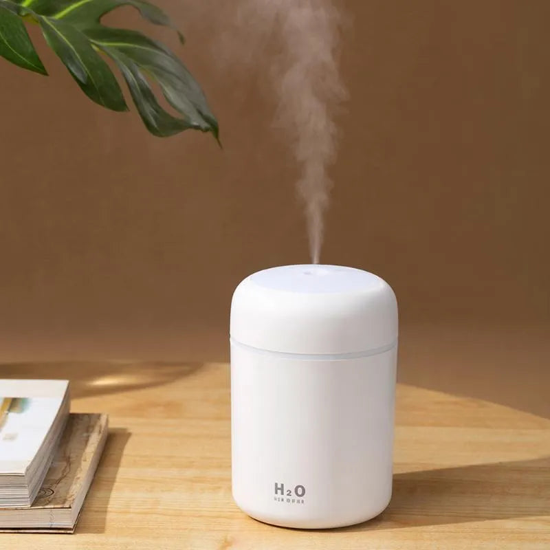 Pink, white, and navy blue USB mini silent humidifier with LED lights on a desk