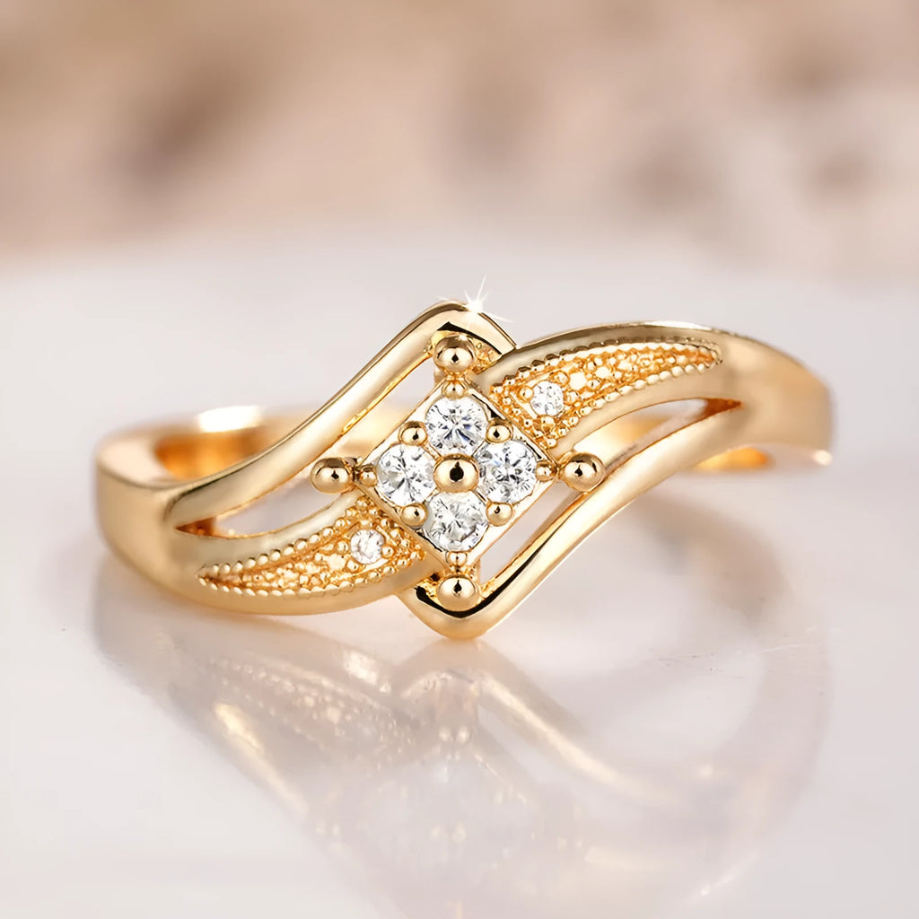 Yellow gold women's geometric diamond ring with a small inlaid zircon stone, shown on a copper band.