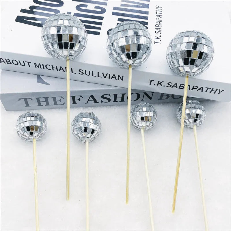 Glass disco ball cake decoration with wooden stick in various sizes on a cake