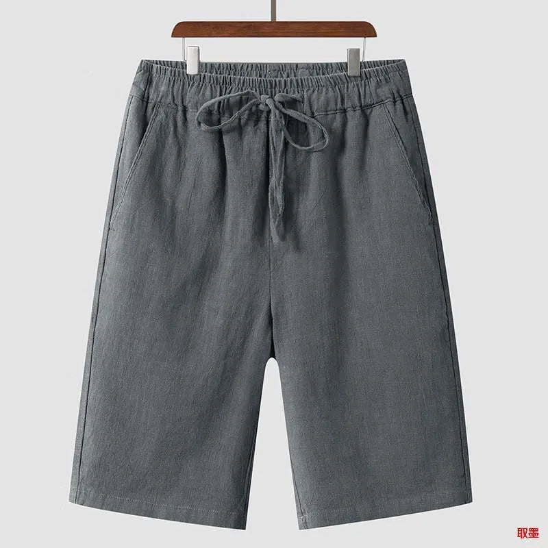 Pair of beige men's casual linen shorts with a loose fit and cropped length on a plain background.