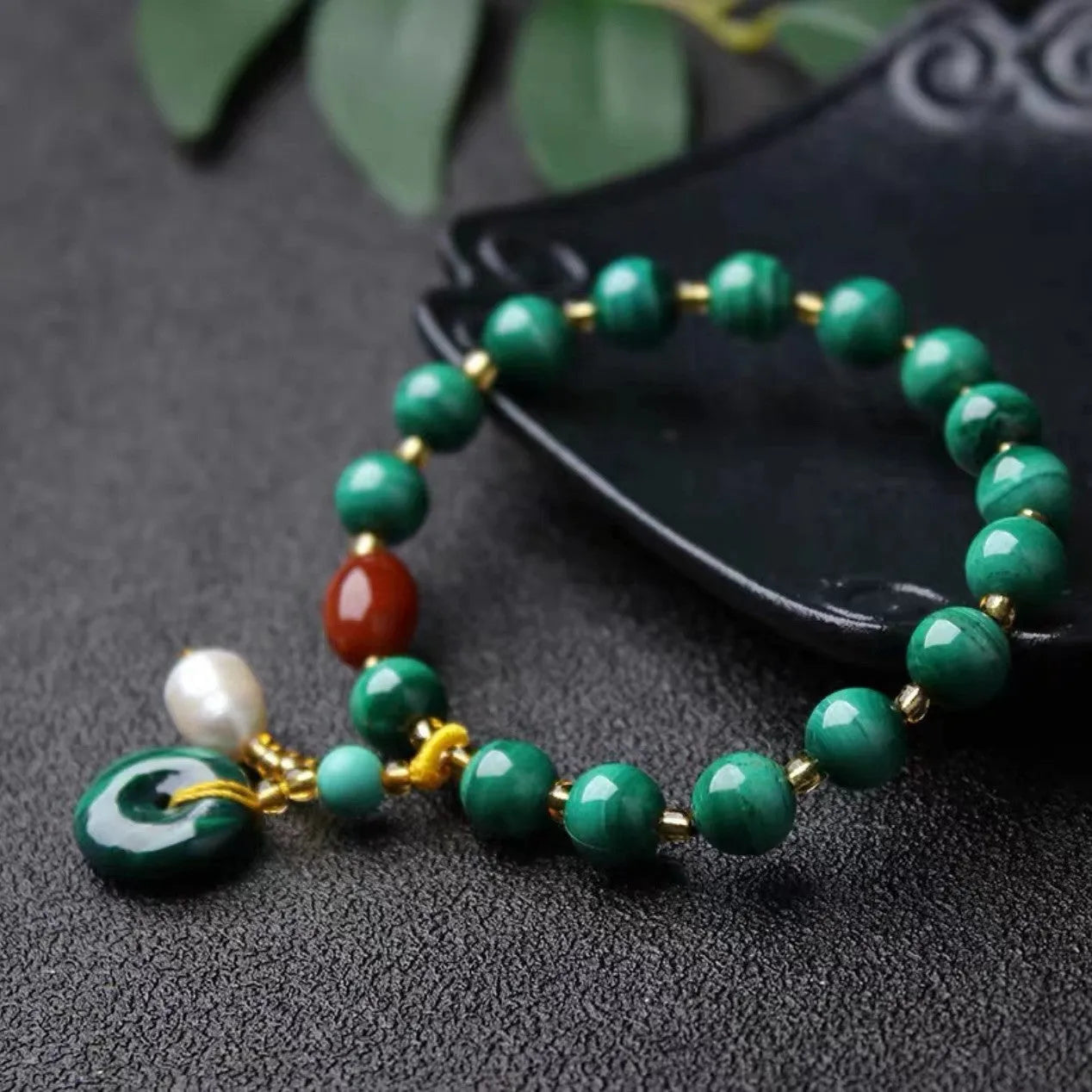 Close-up of a natural malachite and red agate bracelet with 7-8mm barrel beads on a wrist.