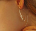 Creative abstract face contour earrings in metal gold finish on a white background