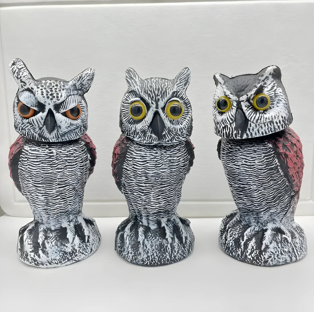 Plastic artificial owl bird scarer with a shaking head, shown in a garden setting.