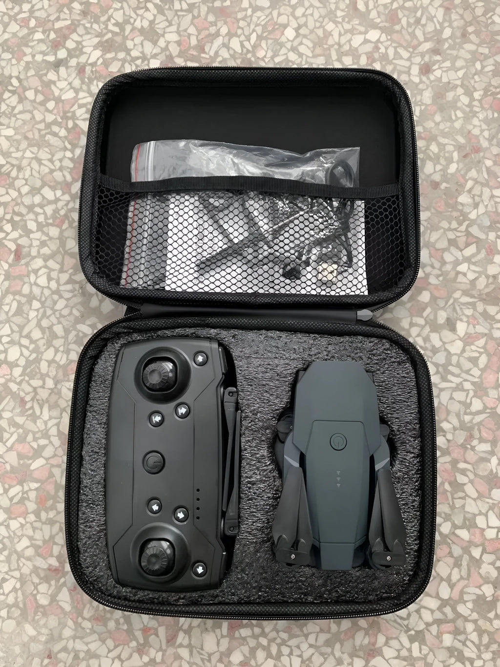 Folding plastic aerial drone with high-definition wide-angle camera, 26cm body, folded to 12cm, on a plain background