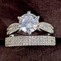 White gold coloured alloy geometric wedding ring bracelet with a round element on a size 7 finger.