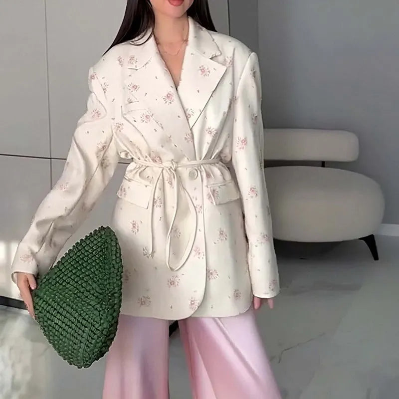 White suit jacket with a lace-up collar and a fitted waist on a model.