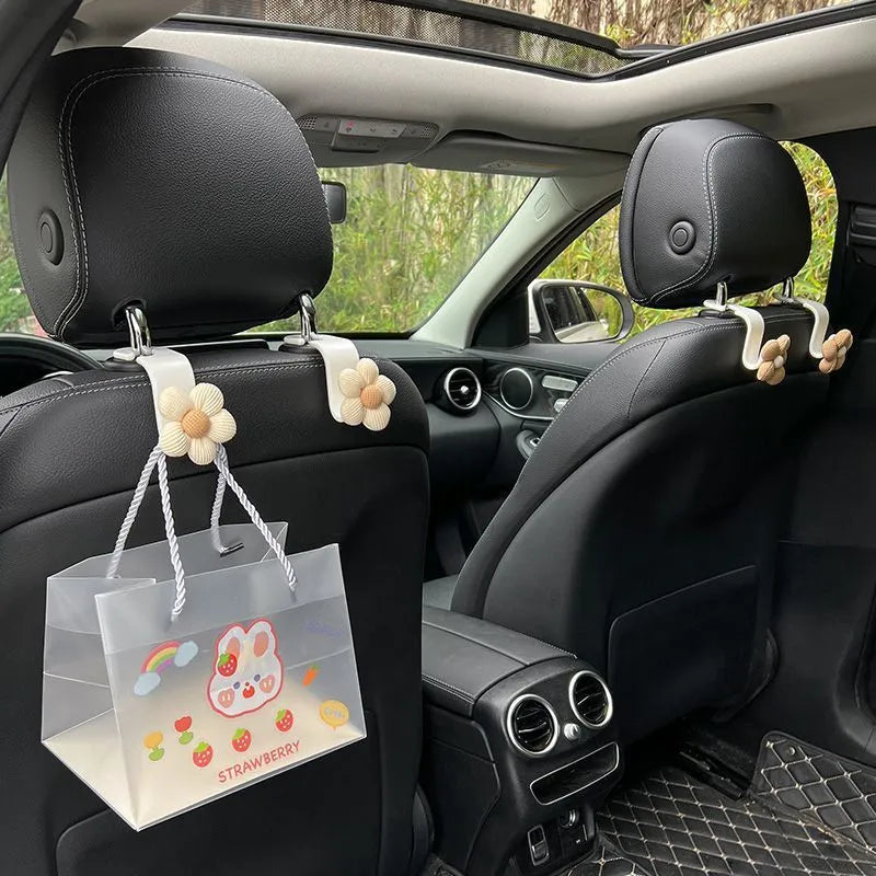Khaki-coloured plastic car seat hook with a small decorative flower for storage.