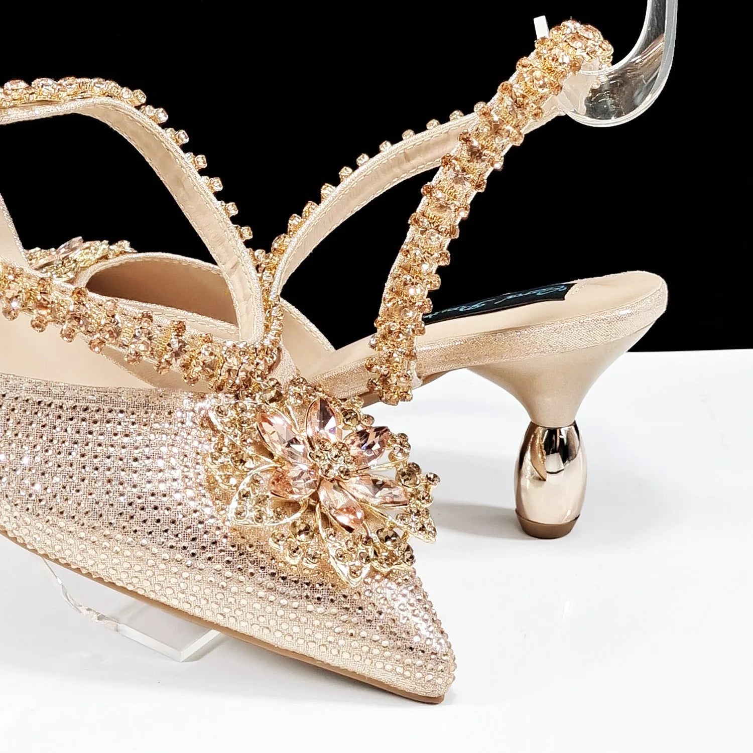 Women's black high heel shoe and matching clutch bag with floral rhinestone decoration and chain strap.